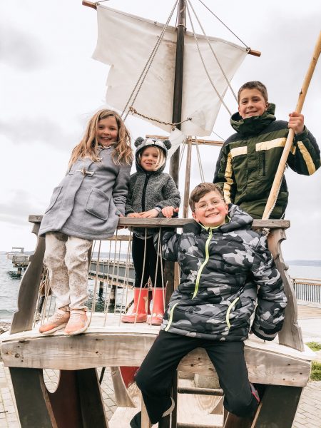 Four children together on a pirate ship play structure
